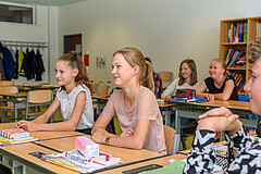 Mädchen und Jungen sitzen in einem Klassenraum an Tischen